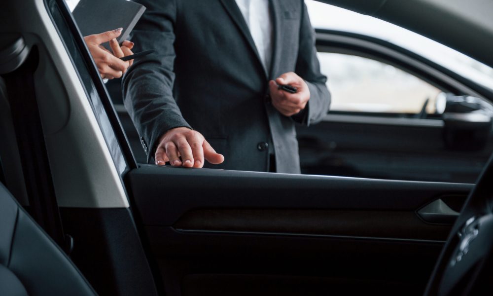 Photo from the inside of vehicle. Female customer and modern stylish bearded businessman in the automobile saloon.