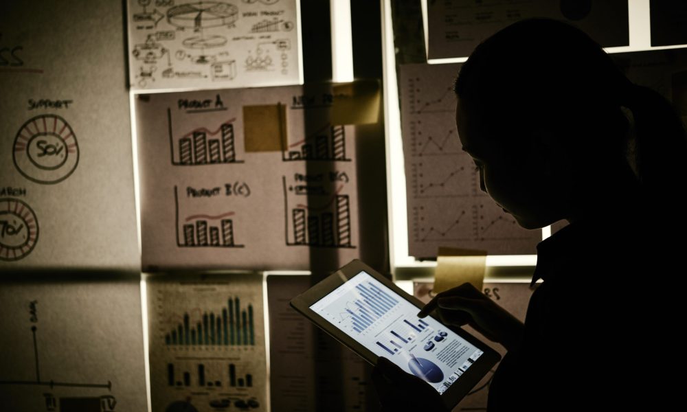 Business lady analyzing chart on tablet computer in dark office